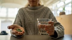 Una mujer prepara una serie de pastillas para tomarse. 