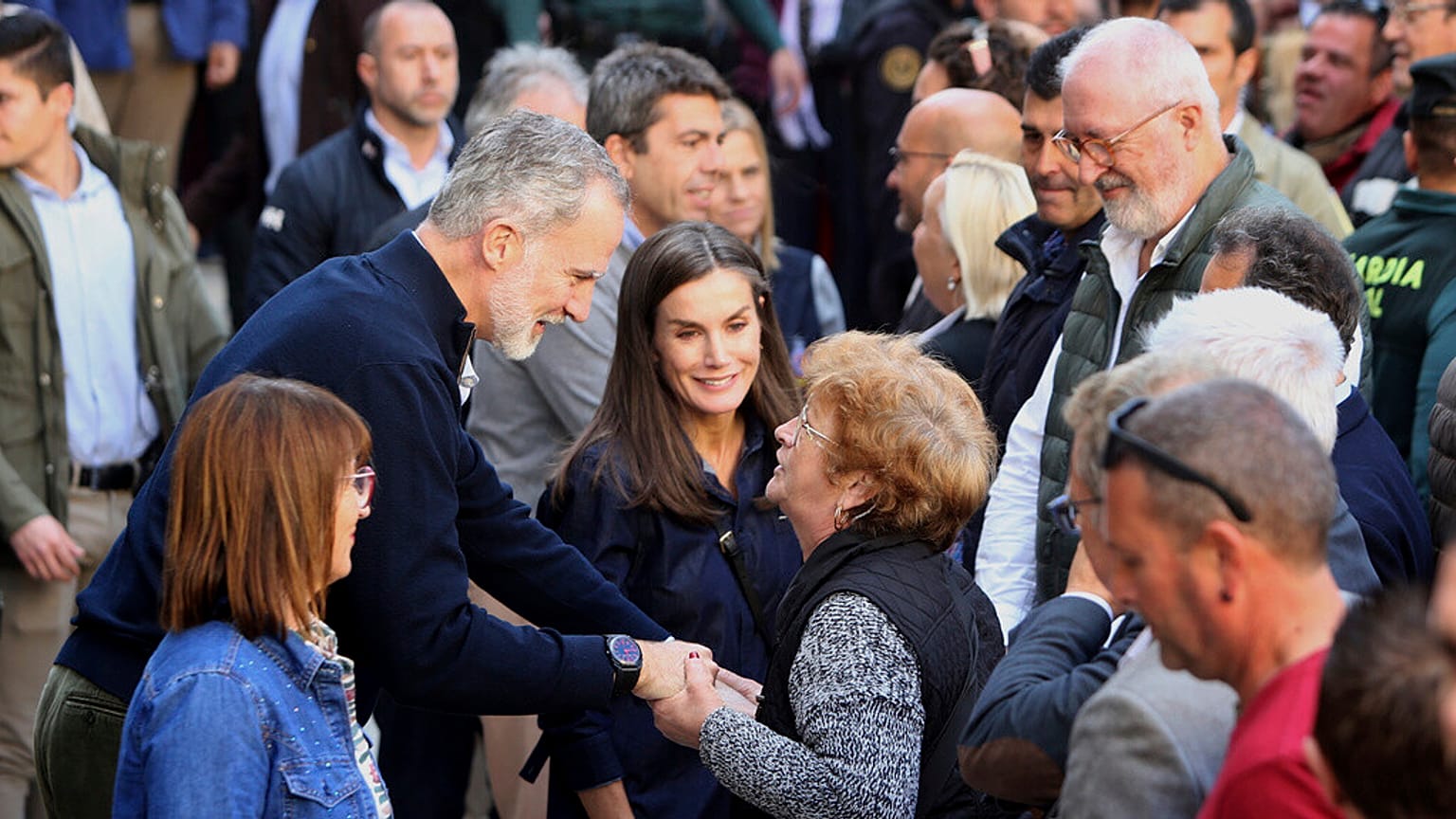Spain's King Felipe VI speaks with a woman next to Spain's Queen Letizia, as they visit the area devastated by last month's flooding in Chiva, near Valencia, Spain