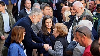 Spain's King Felipe VI speaks with a woman next to Spain's Queen Letizia, as they visit the area devastated by last month's flooding in Chiva, near Valencia, Spain