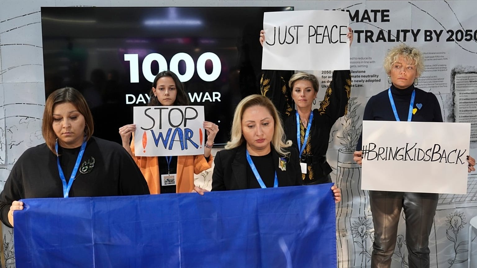 Demonstrators hold signs marking 1,000 days of war in Ukraine at COP29. 