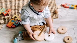Um bebé brinca com brinquedos de madeira.