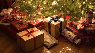 Regalos de Navidad envueltos bajo un árbol luminoso