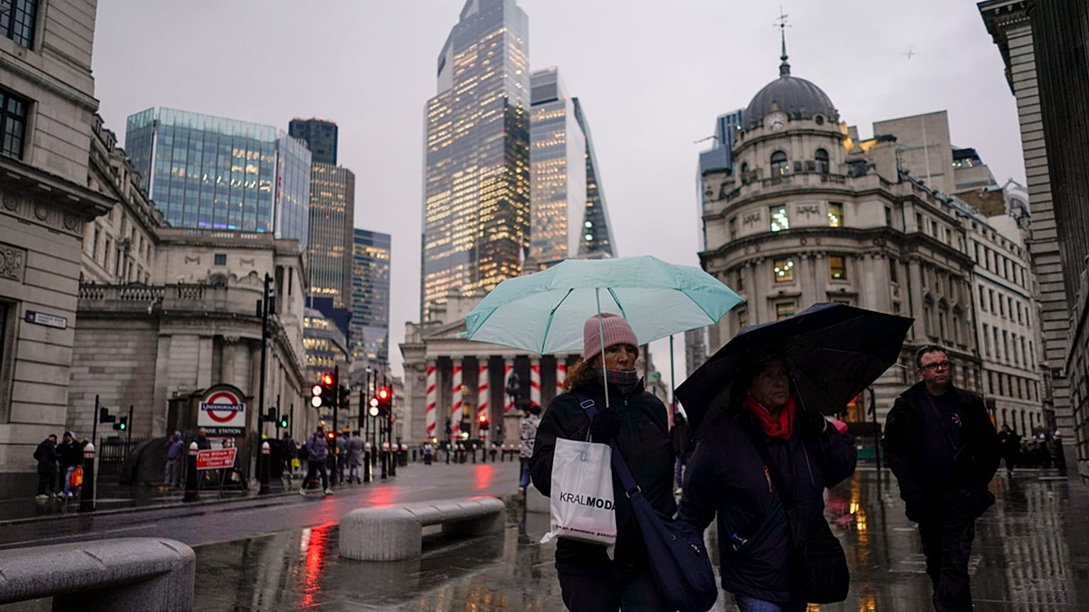 People hold umbrellas as they walk in front of the Bank of England, at the start of a week that is set to see the temperatures drop, in London, Monday, Nov. 18, 2024