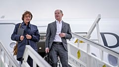 German Chancellor Olaf Scholz, right, and his wife Britta Ernst walk down the gangway of the Airbus A350 after landing at the military section of BER Berlin-Brandenburg Airpor