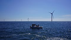 Workers aboard a small boat check lines of seaweed and mussels crops at Kriegers Flak offshore wind farm in Denmark. 