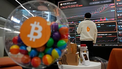 Zdjęcie pliku - Pracownik obserwuje elektroniczny szyld wyświetlający ceny Bitcoina 