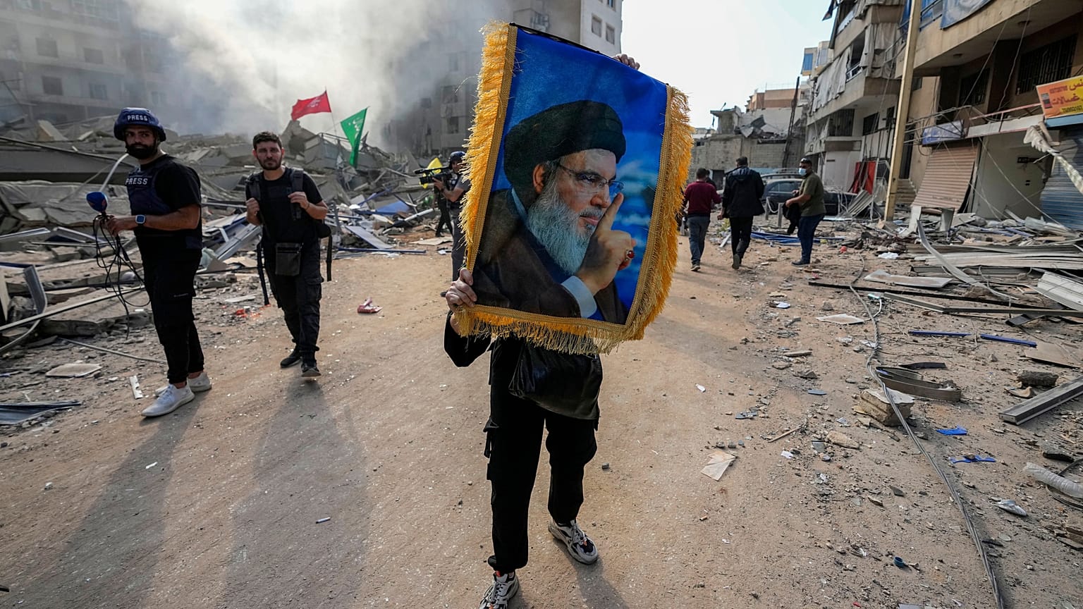 Beyrut Dahiye'de İsrail'in hava saldırısı düzenlediği yerde bir adam elinde öldürülen Hizbullah lideri Hasan Nasrallah'ın resmini tutuyor ve İsrail karşıtı sloganlar atıyor.