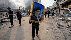 Um homem segura uma fotografia do líder do Hezbollah, Hassan Nasrallah, e grita slogans anti-israelitas no local de um ataque aéreo israelita em Dahiyeh, Beirute.