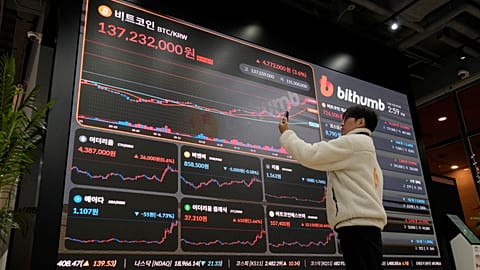 An employee takes a picture of an electronic signboard displaying the prices of Bitcoin and other cryptocurrencies at the lounge of Bithumb cryptocurrency exchange in Seoul
