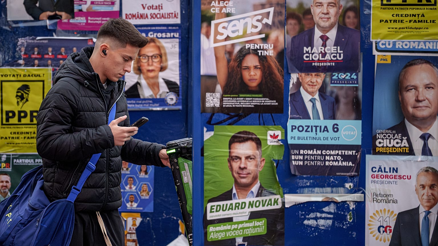 Un joven junto a paneles con carteles electorales en Bucarest, 22 de noviembre de 2024.
