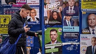 Un joven junto a paneles con carteles electorales en Bucarest, 22 de noviembre de 2024.