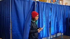A woman prepares to cast her vote in the country's presidential elections, in Bucharest, Romania, Sunday, Nov. 24, 2024.