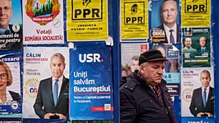 Un hombre camina entre paneles que muestran carteles electorales en Bucarest, 22 de noviembre, 2024