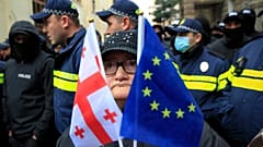Uma mulher com uma bandeira da UE e uma bandeira nacional da Geórgia está em frente à polícia perto do edifício do Parlamento em Tbilisi, Geórgia, na segunda-feira.
