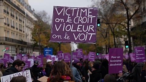A protestor holds a placard reading "Victim we believe you. Rapist we see you" during a march for the International Day for the Elimination of Violence Against Women in Paris.