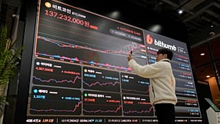 موظف يلتقط صورة للافتة إلكترونية تعرض أسعار البيتكوين والعملات المشفرة الأخرى في صالة بورصة Bithumb للعملات المشفرة في سيول، كوريا الجنوبية، الخميس 21 نوفمبر/تشرين الثاني 2024