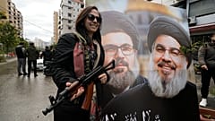 زنی در کنار تصویری از دو رهبر کشته شده حزب الله حسن نصرالله و هاشم صفی الدین به هنگام بازگشت به ضاحیه در بیروت، لبنان، پس از آتش بس بین اسرائیل و حزب الله، چهارشنبه، ۲۷ نوامبر