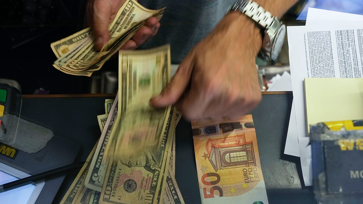 تصویر پرونده ای از یک صندوقدار که اسکناس 50 یورویی را با دلار آمریکا در یک دفتر مبادله در رم تغییر می دهد