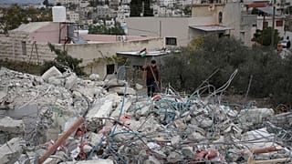 طفل يحمل العلم الفلسطيني فوق الدمار الذي أحدثته الحرب على غزة