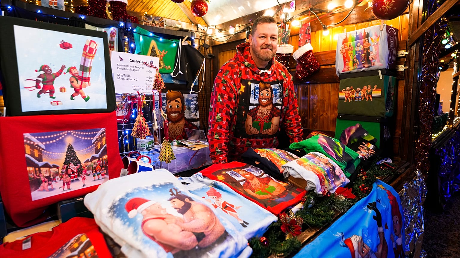 Artist Paul Middleton stands in his shop with shirts he designed at the LGBTQ+ Christmas market "Christmas Avenue" at Nollendorfplatz the for in Berlin.