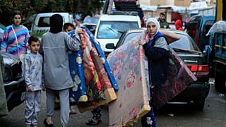 Sayda'da İsrail ve Hizbullah arasındaki ateşkesin yürürlüğe girmesinin ardından köylerine dönmeye hazırlanan yerinden edilmiş aileler yatak taşıyor, 27 Kasım 2024