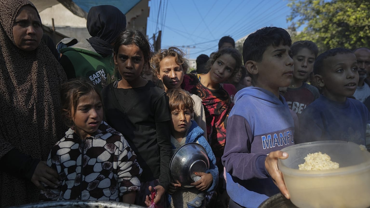 Palesztin gyerekek sorban állnak a gázai Deir al-Balah egyik ételosztó konyhájánál