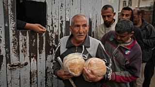 Ηλικιωμένος άνδρας κρατάει δύο καρβέλια ψωμί σε σημείο διανομής τροφίμων στην εμπόλεμη Γάζα
