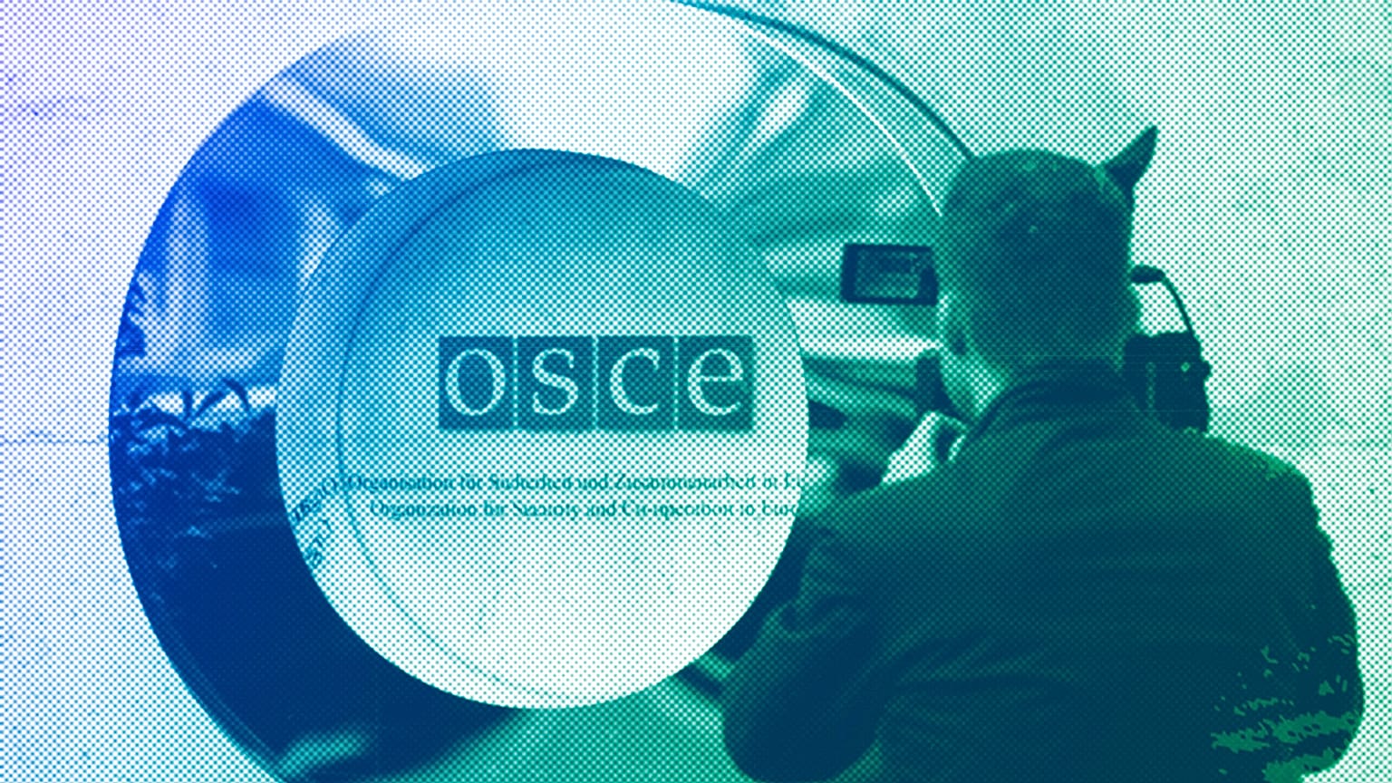 A cameraman films the OSCE logo outside the venue of an OSCE Parliamentary Assembly, in Vienna, February 2023