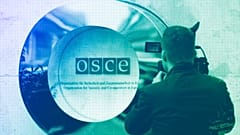 A cameraman films the OSCE logo outside the venue of an OSCE Parliamentary Assembly, in Vienna, February 2023