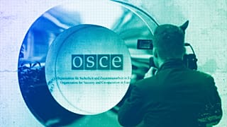 A cameraman films the OSCE logo outside the venue of an OSCE Parliamentary Assembly, in Vienna, February 2023