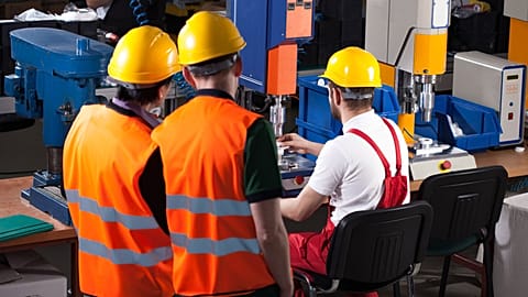 Three workers in safety helmets working in a factory