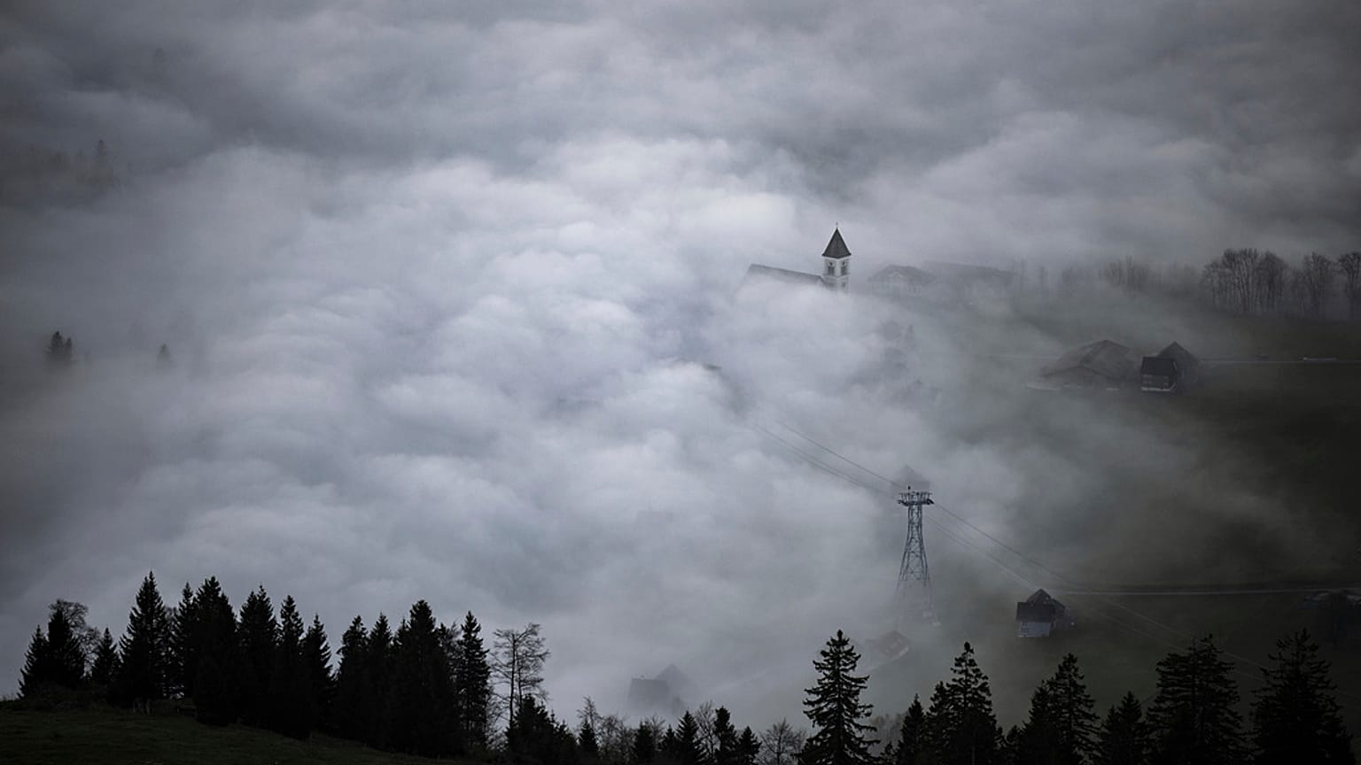 A church tower rises through the fog in Bruelisau, Switzerland. 4 November 2024.