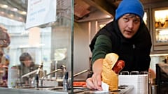 Ein Verkäufer serviert einen Hotdog an einem traditionellen Würstchenstand 
