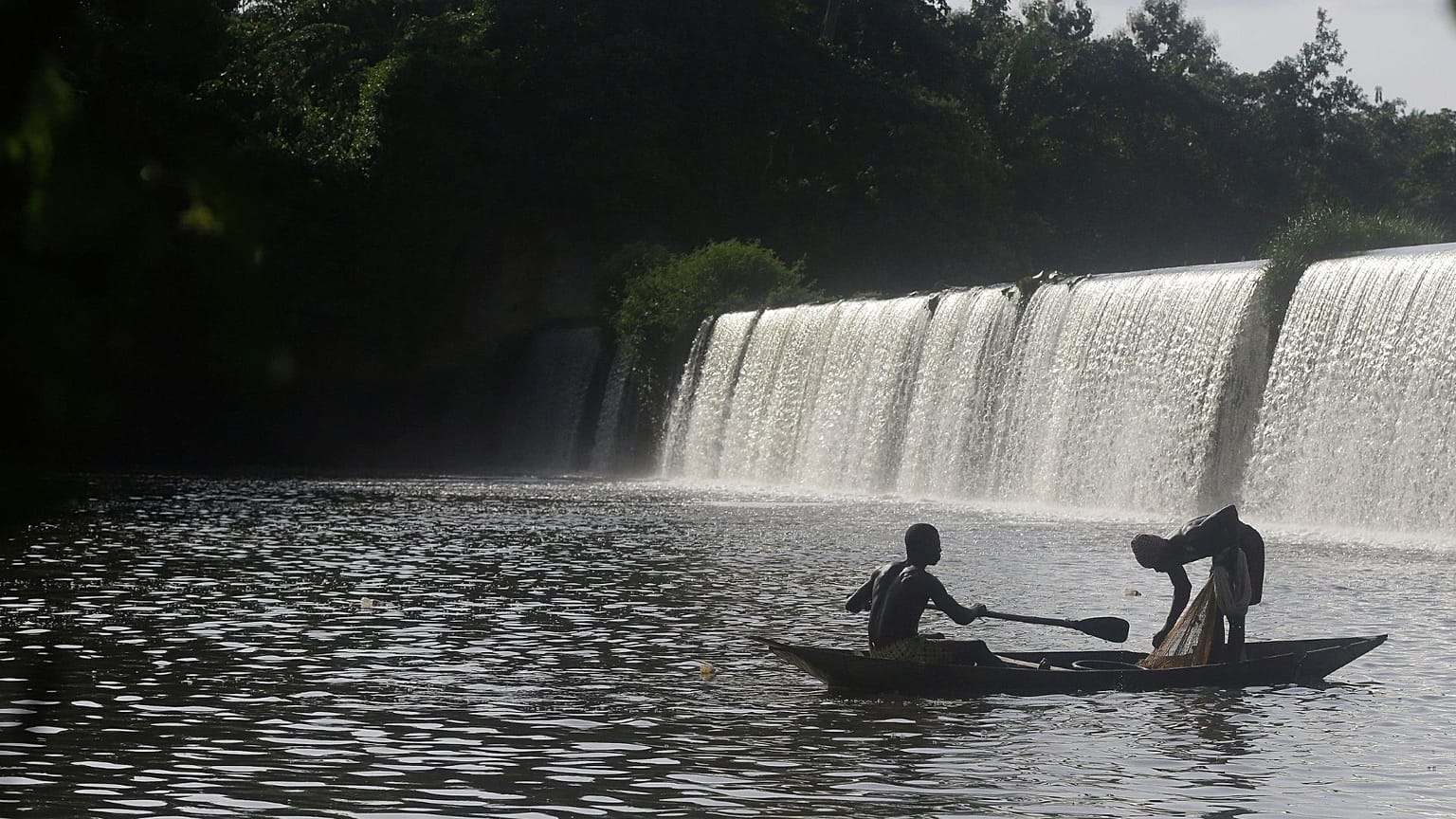Pescatori remano con la loro canoa vicino a una diga che alimenta il fiume sacro a Esa-Odo, in Nigeria, sabato 28 maggio 2022. 