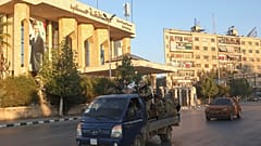 مسلحون في الفصائل المعارضة على متن مركبة عسكرية أمام مبنى محافظة حلب، السبت 30 نوفمبر/ تشرين الثاني 2024.