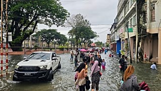 سكان يسيرون في شارع غمرته المياه بعد هطول أمطار موسمية غزيرة وسط مدينة كوتا بهارو، كيلانتان، ماليزيا، الجمعة 29 نوفمبر 2024. 