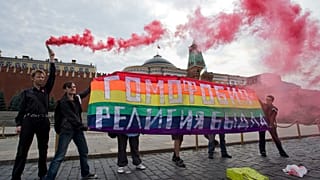 Activistas por los derechos de los homosexuales sostienen una pancarta en la que se lee Homofobia - la religión de los matones durante su acción de protesta.