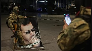 Muhalif bir militan Halep yakınlarında Esad'ın sökülmüş posteriyle fotoğraf çekiliyor / 30 Kasım 2024