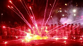 Göstericiler, 1 Aralık 2024 Pazar günü erken saatlerde Gürcistan'ın Tiflis kentindeki parlamento binası dışında polise fişek atıyor