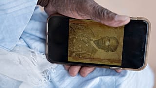 Biram Senghor, whose father was killed in 1944, holds a phone with a photo of his father, in Rufisque, Senegal, Thursday, Nov. 28, 2024. (AP Photo/Sylvain Cherkaoui)
