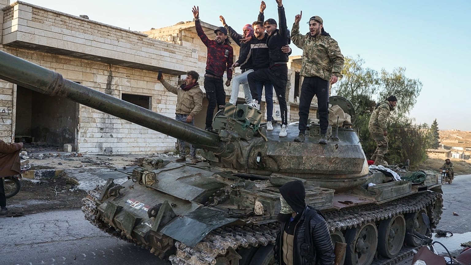 Apoiantes da oposição síria em cima de um tanque do exército sírio capturado na cidade de Maarat al-Numan, a sudoeste de Alepo, Síria, sábado, 30 de novembro de 2024. 