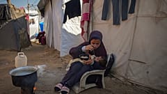 16 yaşındaki Asma El-Harobi, Gazze Şeridi'ndeki yerinden edilmiş Filistinliler için kurulan kampta 10 aylık kız kardeşine suyla karışık süt içiriyor, 1 Aralık, 2024.