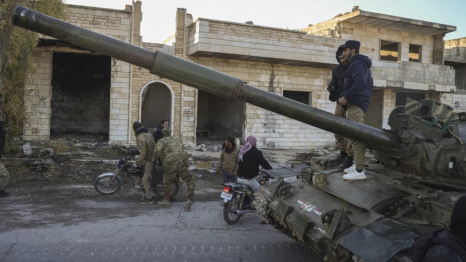 Muhalif militanların destekçileri, Suriye'nin Halep kentinin güneybatısındaki Maaret el-Numan kasabasında ordunun ele geçirilen zırhlı aracının üzerinde duruyor