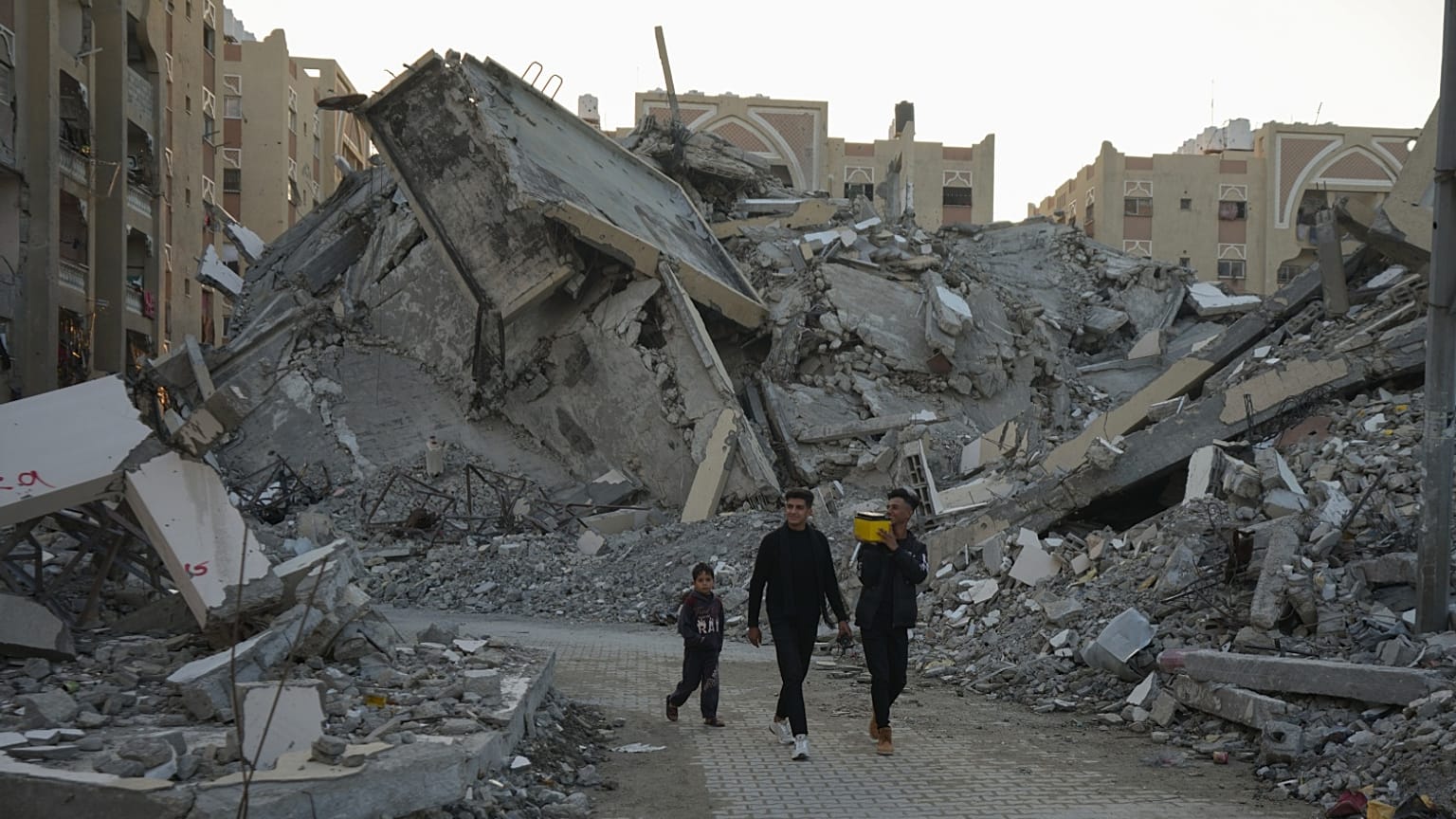 شباب فلسطينيون يتجولون بين أنقاض المباني المدمرة في أحد أحياء خان يونس بقطاع غزة، الأحد 1 ديسمبر 2024.