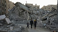 شباب فلسطينيون يتجولون بين أنقاض المباني المدمرة في أحد أحياء خان يونس بقطاع غزة، الأحد 1 ديسمبر 2024.