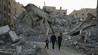 شباب فلسطينيون يتجولون بين أنقاض المباني المدمرة في أحد أحياء خان يونس بقطاع غزة، الأحد 1 ديسمبر 2024.