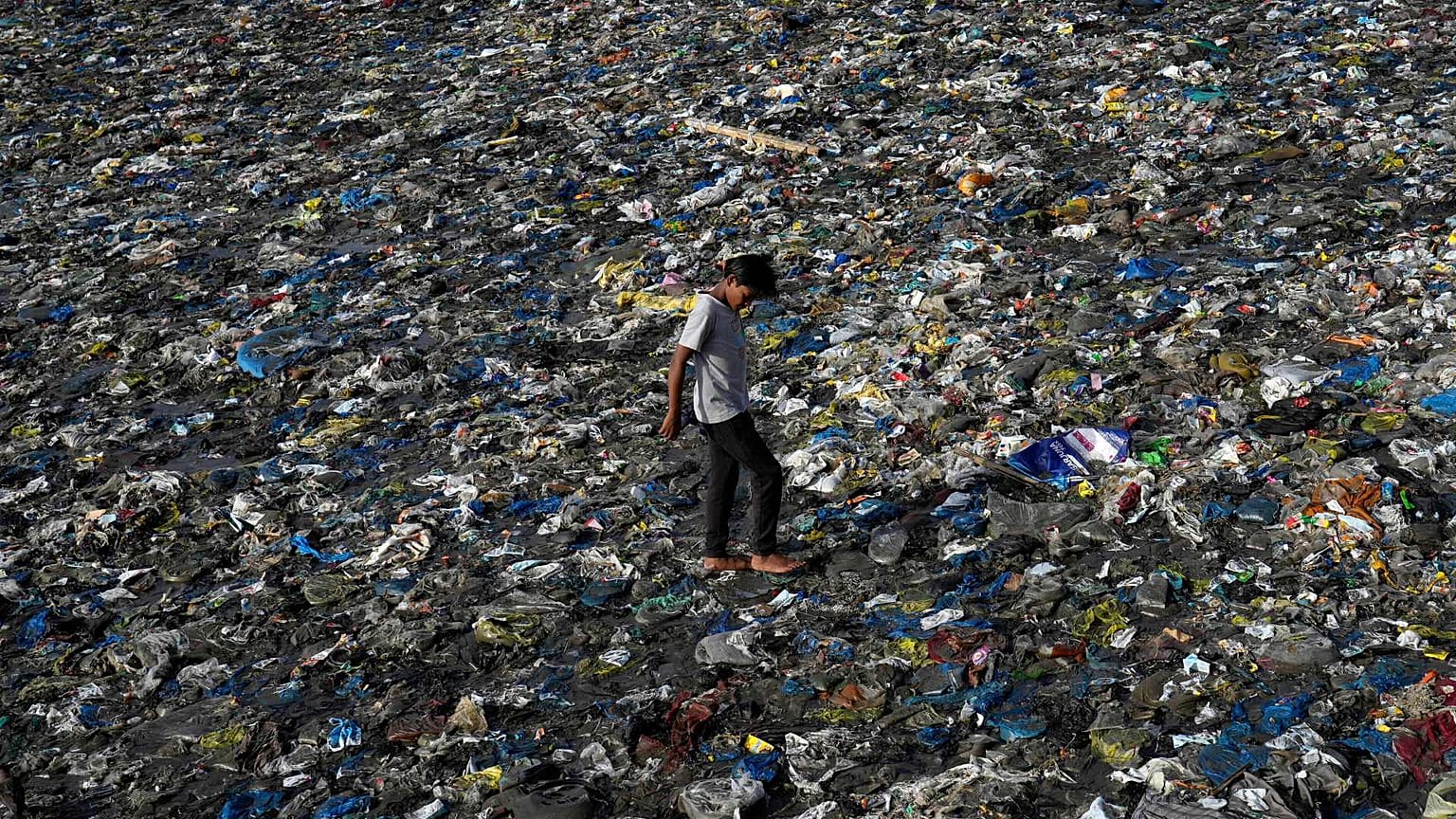 A boy walks on the plastic waste at the Badhwar Park beach on the Arabian Sea coast on World Environment Day in Mumbai, India, Monday, June 5, 2023.