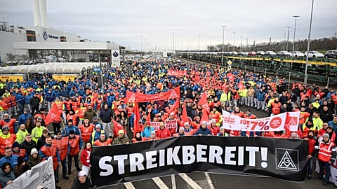 Volkswagen workers wave trade union flags as they demonstrate on the first day of a nationwide-warning strike, outside a VW plant in Zwickau, Germany