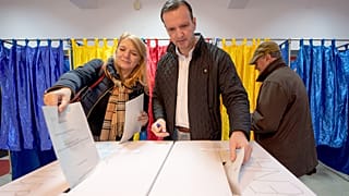 A man and a woman post their votes in the country's parliamentary elections, in Bucharest, 1 December 2024