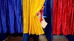 Une femme sort isoloir aux couleurs du drapeau roumain, lors des élections parlementaires du pays, à Bucarest, dimanche 1er décembre 2024. 